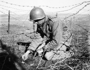 Un soldat français pose une mine au sein d’un réseau de barbelés (DR).